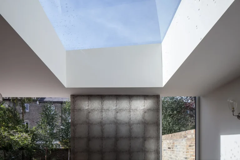 Interior view designed by Trevor Brown Architect, featuring a large skylight and brick wall, with trees visible through a window.