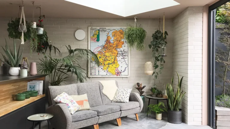 Living room with a gray sofa, plants, and a large map on the wall. A skylight above floods the space with natural light, highlighting Trevor Brown Architect's touch in this beautiful Wood Green home refurbishment.